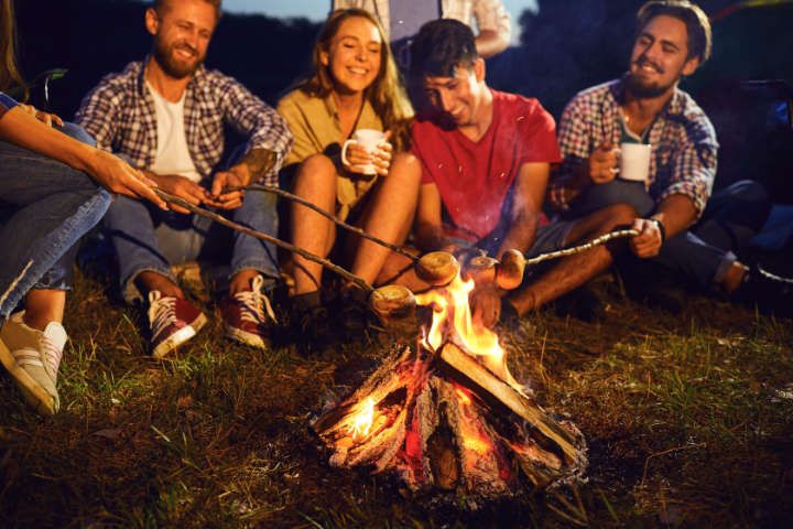 Eine Gruppe von Freunden grillt Marshmallows am Lagerfeuer