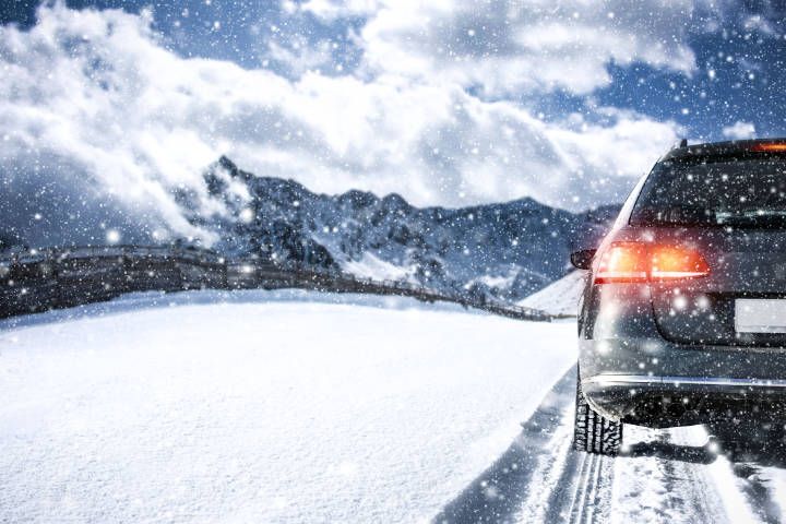 Auto fährt durch die verschneite Alpenstraße